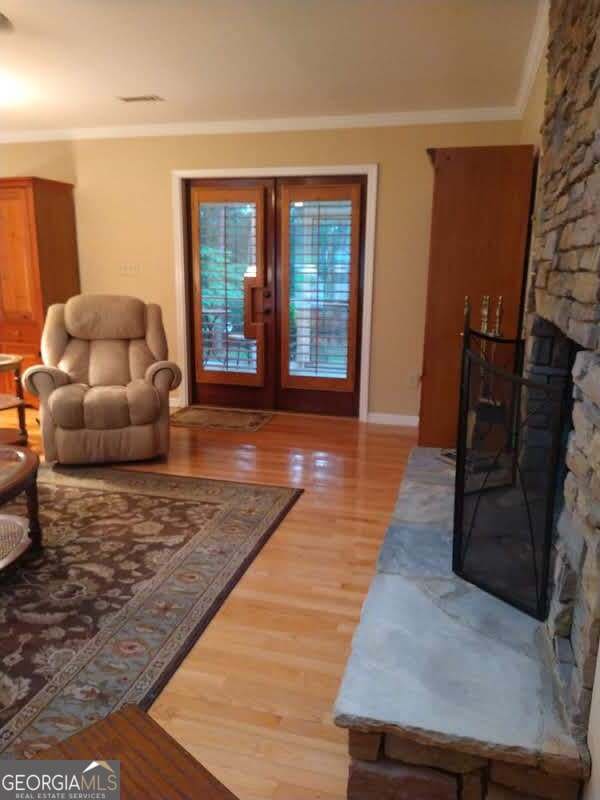 living room with wood-type flooring, a fireplace, and crown molding