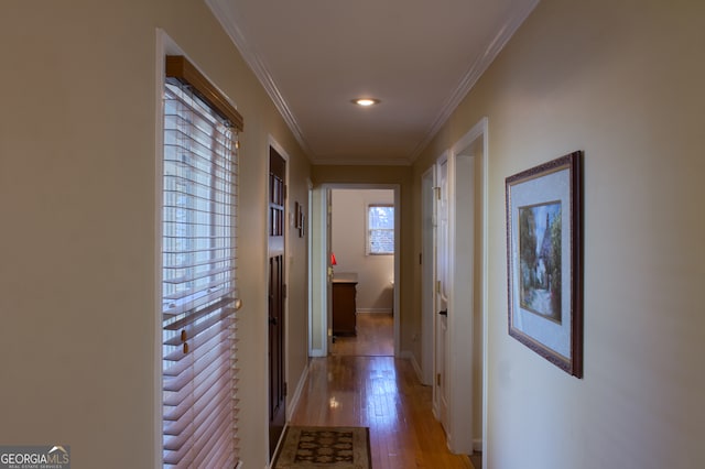 hallway with light wood-type flooring, baseboards, and ornamental molding