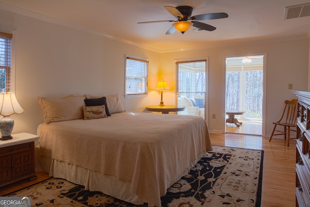 bedroom with ornamental molding, visible vents, light wood-style floors, and ceiling fan