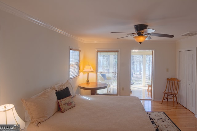 bedroom with light wood-style flooring, visible vents, a ceiling fan, ornamental molding, and a closet