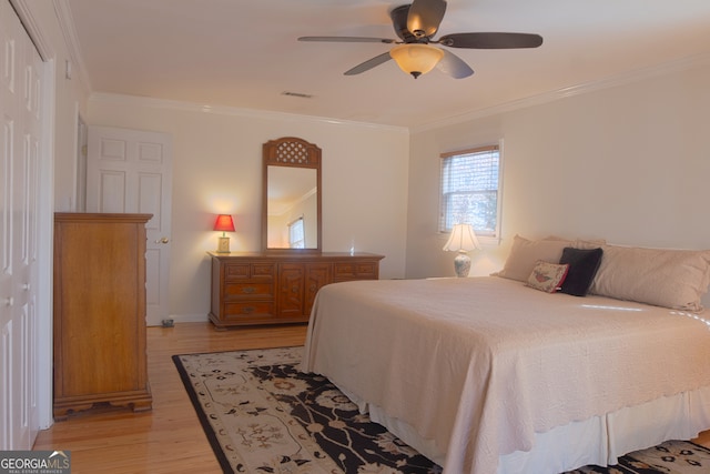 bedroom with light wood finished floors, visible vents, a ceiling fan, crown molding, and a closet