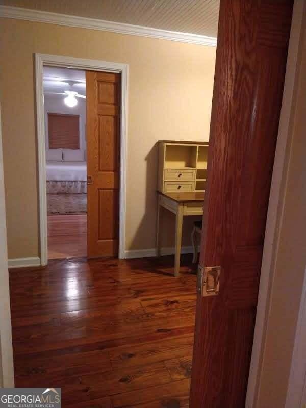 hallway with baseboards, wood finished floors, and crown molding