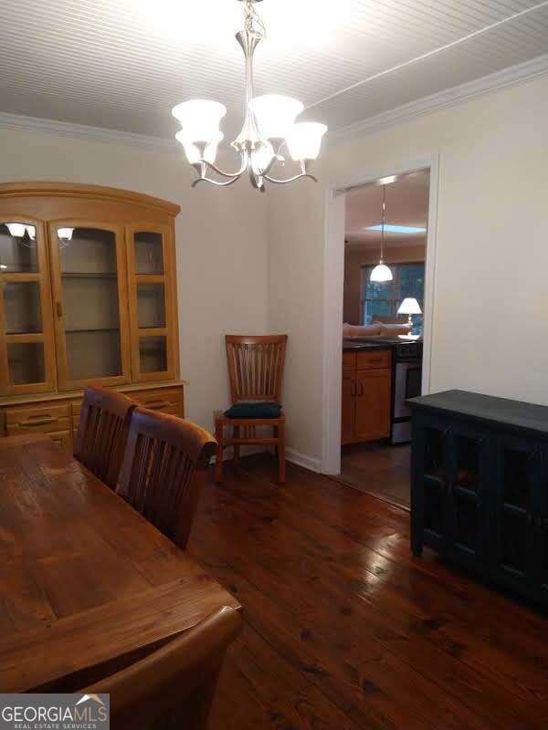 dining room with dark hardwood / wood-style floors, an inviting chandelier, and ornamental molding