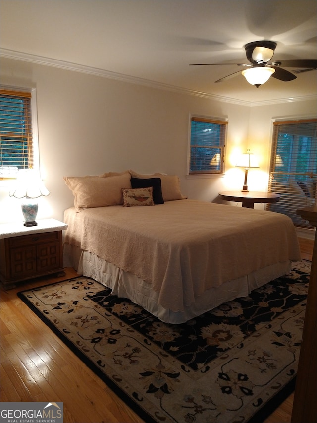 bedroom with crown molding, wood-type flooring, and ceiling fan