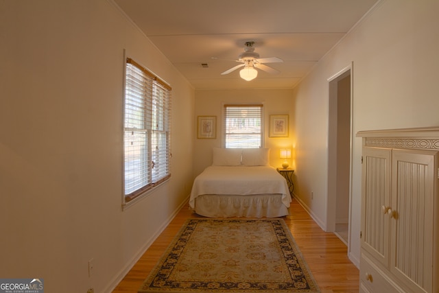 bedroom featuring light wood-style floors, ceiling fan, baseboards, and crown molding