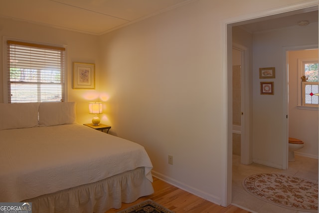 bedroom with ornamental molding, light wood-style flooring, and baseboards