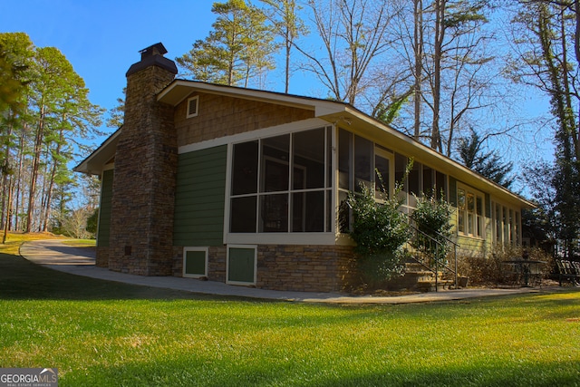 view of side of property with a sunroom, a chimney, and a yard