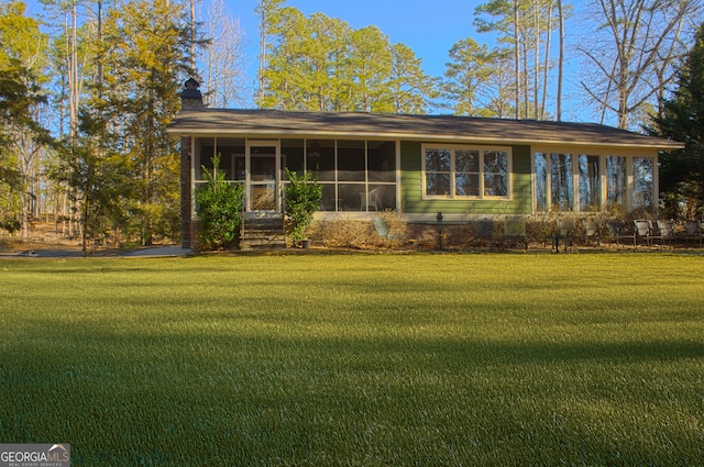 exterior space with a chimney, a front yard, and a sunroom