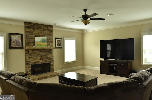 living room featuring carpet floors, a stone fireplace, crown molding, and ceiling fan