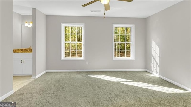 carpeted spare room with ceiling fan, plenty of natural light, and sink