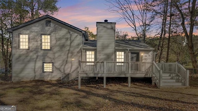 back house at dusk with a wooden deck