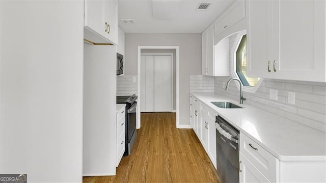 kitchen with sink, white cabinets, stainless steel appliances, and light hardwood / wood-style flooring