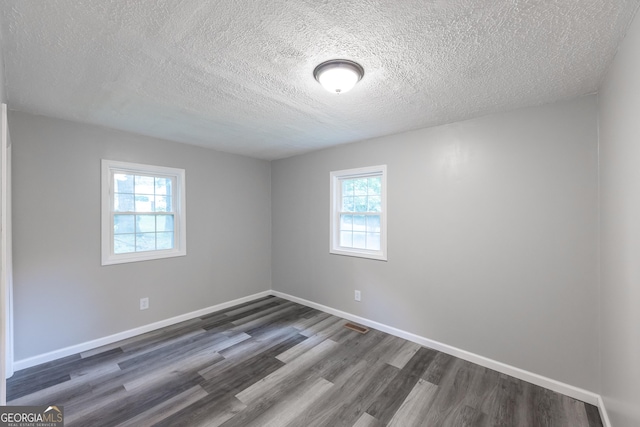 spare room with dark wood-type flooring, a textured ceiling, and baseboards