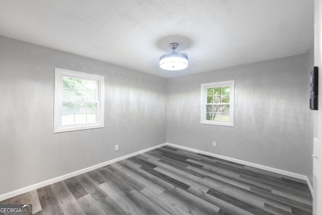 unfurnished room with dark wood-style flooring, plenty of natural light, and baseboards
