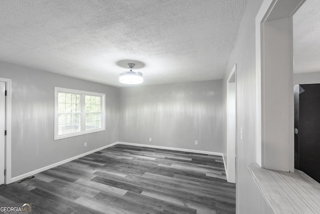 empty room with dark wood-style floors, a textured ceiling, visible vents, and baseboards