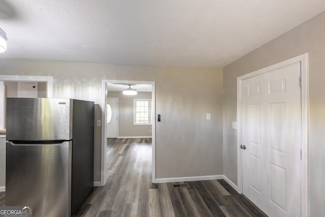 kitchen with visible vents, baseboards, dark wood-type flooring, freestanding refrigerator, and a textured ceiling