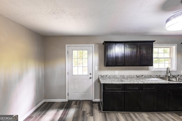 kitchen featuring a textured ceiling, wood finished floors, a sink, and baseboards