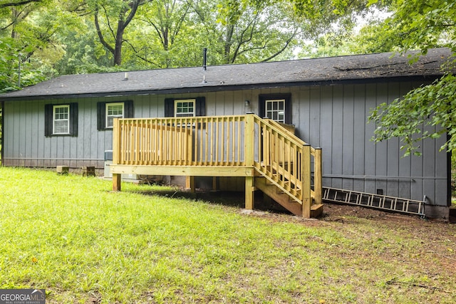 rear view of house with roof with shingles, a yard, a deck, and stairs