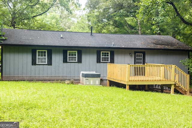 back of house with roof with shingles, a yard, a wooden deck, and central AC unit