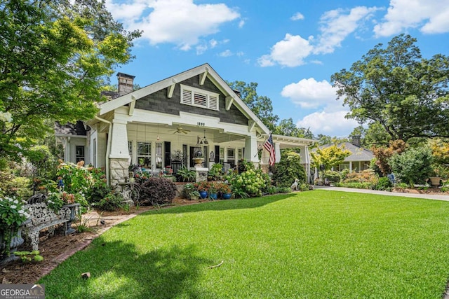 back of property featuring ceiling fan and a yard