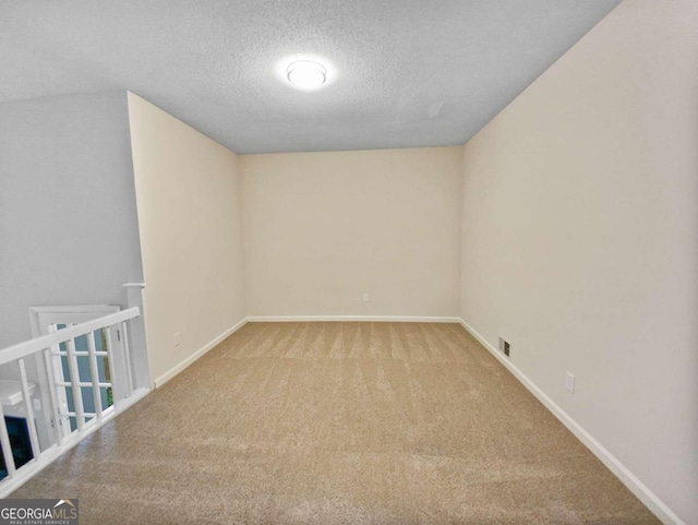 carpeted empty room with a textured ceiling