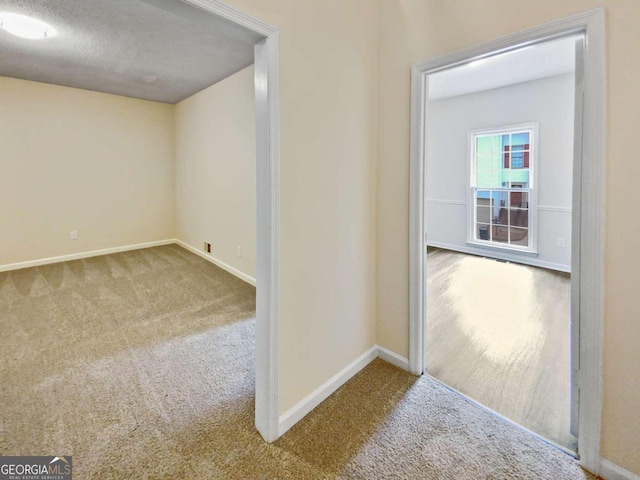 hallway with a textured ceiling and carpet