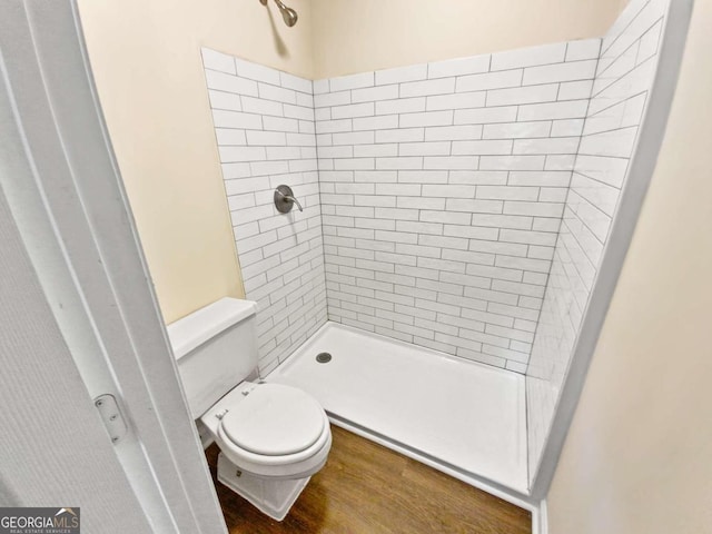 bathroom with a tile shower, hardwood / wood-style flooring, and toilet