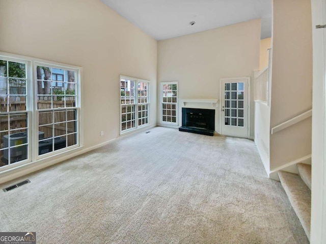 unfurnished living room with light carpet and a high ceiling