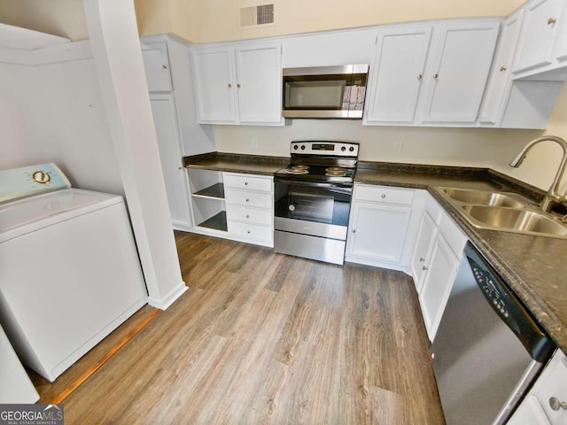 kitchen with sink, appliances with stainless steel finishes, white cabinets, washer / clothes dryer, and light wood-type flooring