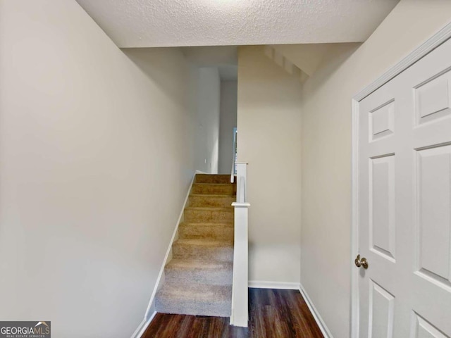 staircase with wood-type flooring and a textured ceiling