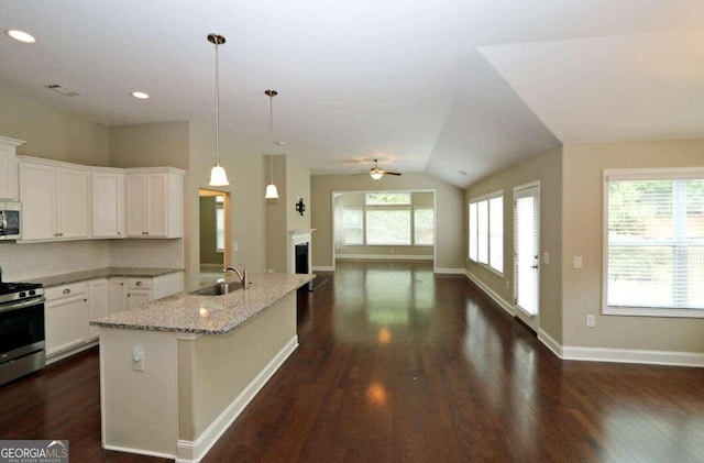 kitchen featuring white cabinetry, hanging light fixtures, a kitchen island with sink, stainless steel appliances, and light stone countertops