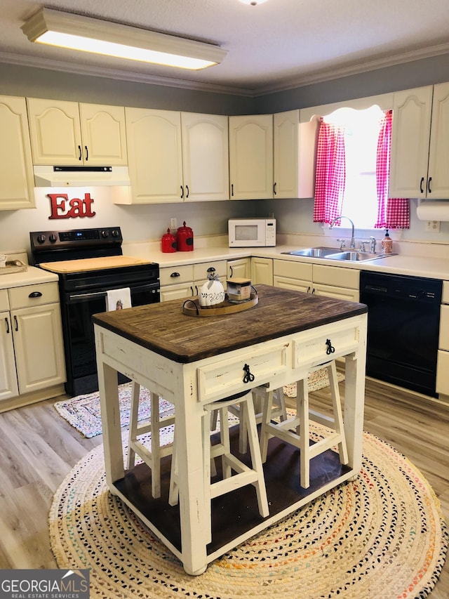 kitchen with sink, light hardwood / wood-style flooring, black appliances, and ornamental molding