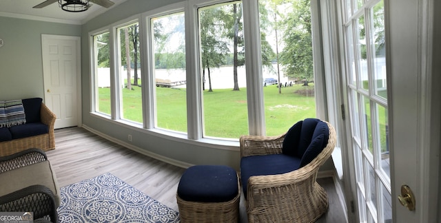 sunroom / solarium with a wealth of natural light, ceiling fan, and a water view