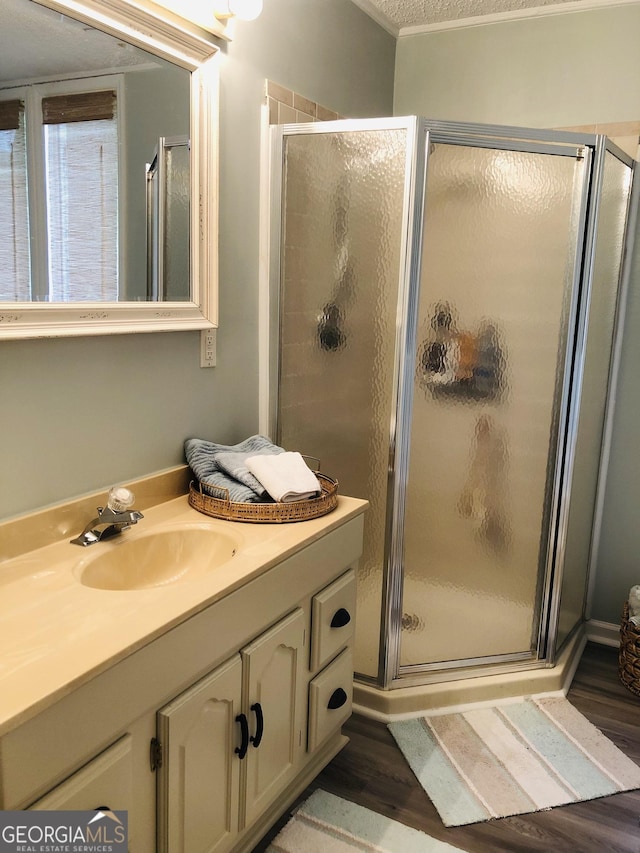 bathroom featuring hardwood / wood-style flooring, vanity, an enclosed shower, and a textured ceiling