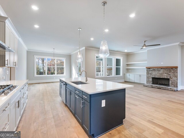 kitchen with a fireplace, sink, decorative light fixtures, light hardwood / wood-style flooring, and white cabinets