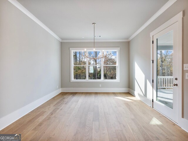 unfurnished dining area featuring light wood-type flooring, an inviting chandelier, and crown molding