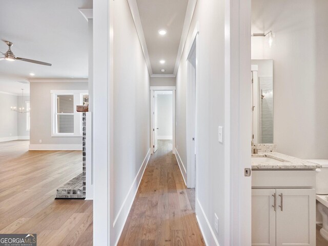 corridor featuring light hardwood / wood-style floors, ornamental molding, and sink