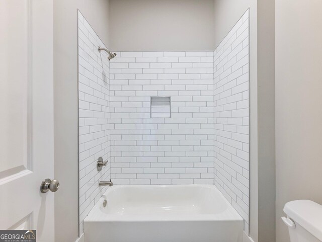 bathroom featuring toilet and tiled shower / bath