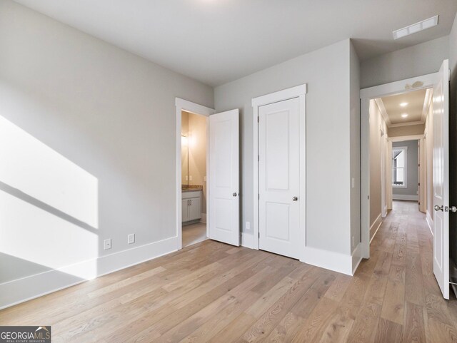 unfurnished bedroom with light hardwood / wood-style floors and connected bathroom