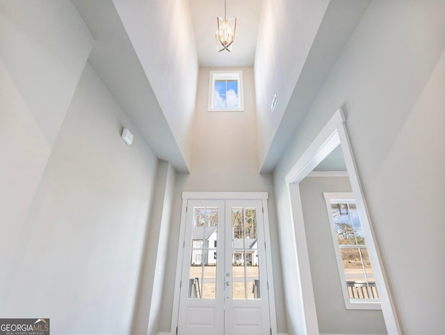 doorway to outside featuring french doors, a notable chandelier, and a high ceiling