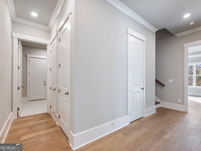 corridor with light hardwood / wood-style floors and ornamental molding