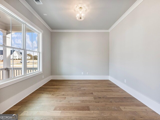 unfurnished room featuring hardwood / wood-style floors and crown molding