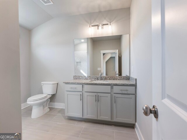 bathroom featuring toilet, vanity, tile patterned floors, and lofted ceiling