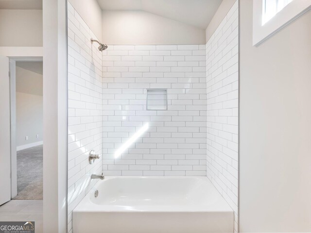 bathroom with tile patterned floors, vaulted ceiling, and tiled shower / bath