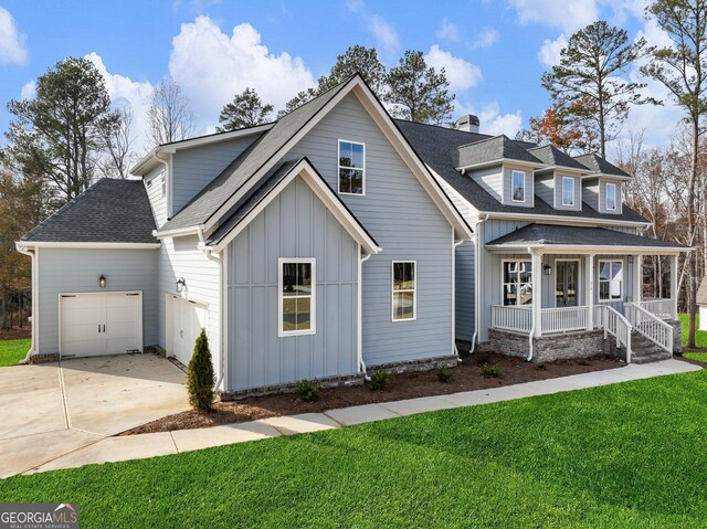 view of front of home with covered porch, a garage, and a front lawn