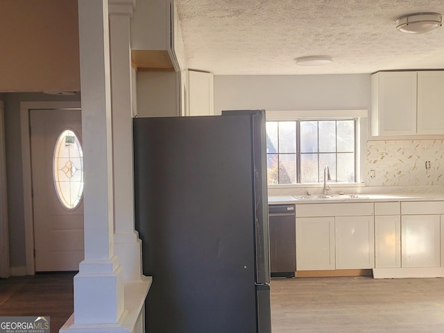 kitchen featuring white cabinetry, sink, black dishwasher, stainless steel fridge, and a textured ceiling