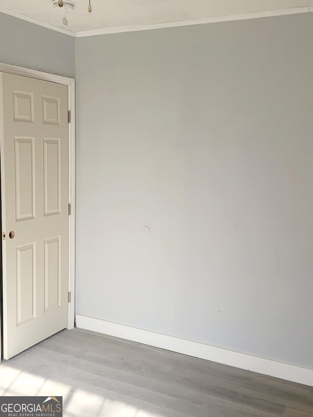 empty room featuring light wood-type flooring and ornamental molding