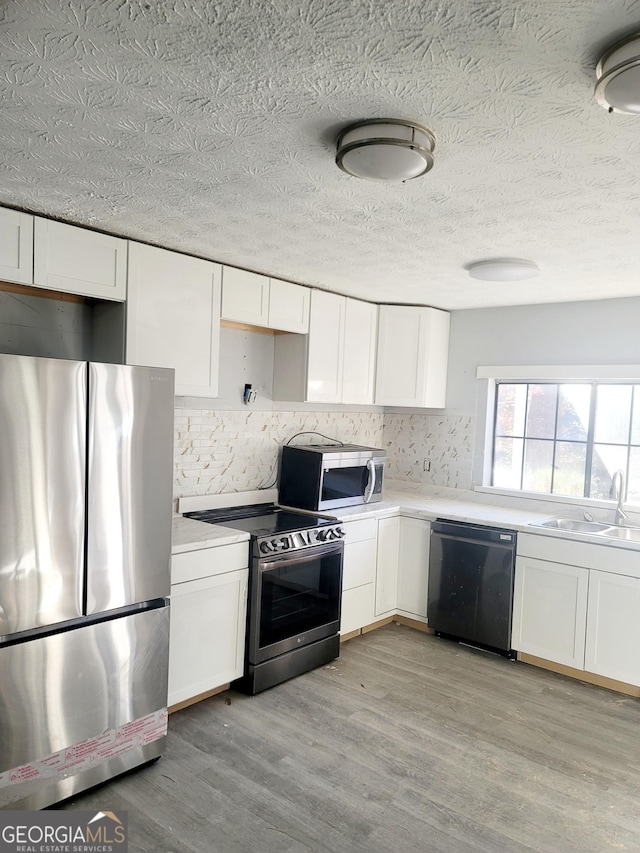 kitchen with light wood-type flooring, white cabinetry, sink, and appliances with stainless steel finishes