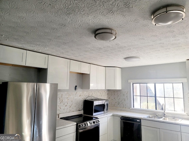 kitchen with a textured ceiling, stainless steel appliances, white cabinetry, and sink