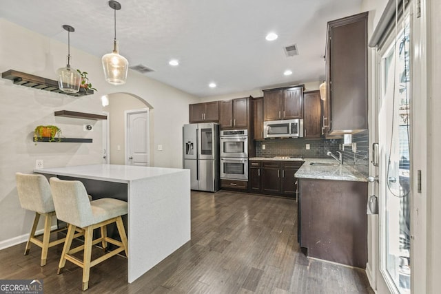 kitchen featuring hanging light fixtures, dark hardwood / wood-style flooring, stainless steel appliances, and backsplash